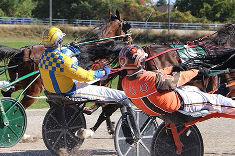 Two jockeys in carts pulling on the reigns of the horses in a race